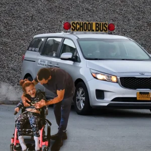 a man helping a young girl in a wheelchair